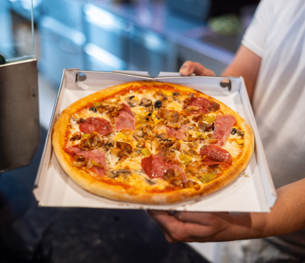 Frische Steinofenpizza mit Salami, Pilzen und Käse auf Tablett – Favorito Graz